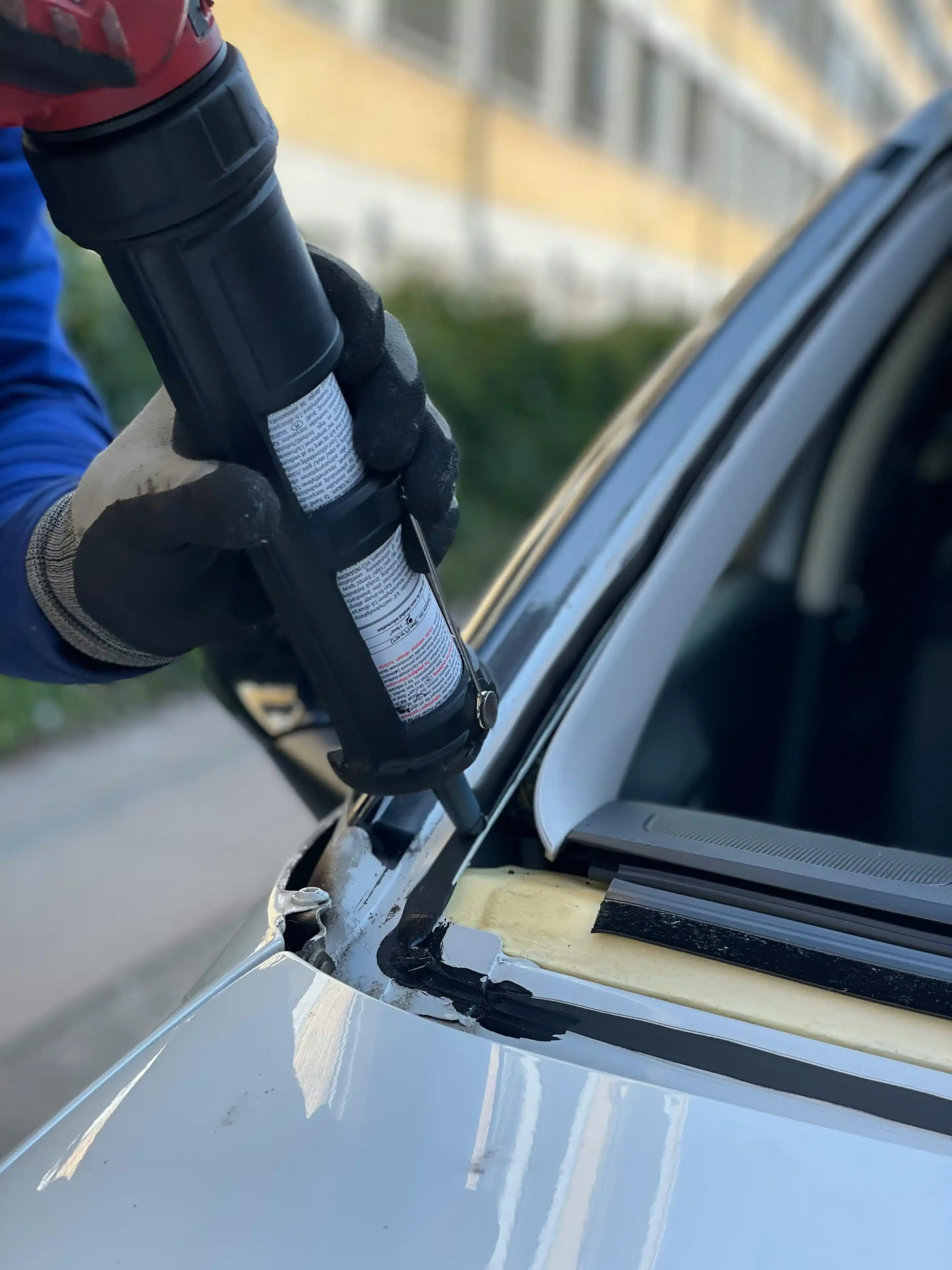 Technician applying urethane primer along a windshield edge